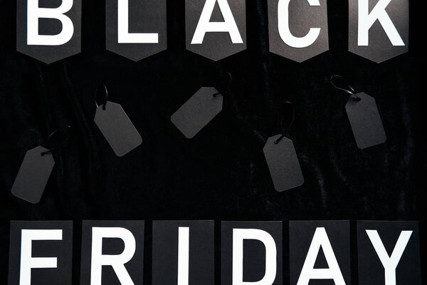 top view of black friday lettering and blank price tags on black background