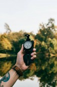 hand of man holding compass on autumnal background