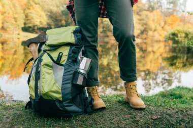 cropped image of traveller legs with backpack on autumnal background clipart