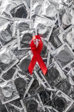 top view of aids awareness red ribbon on silver condoms  clipart