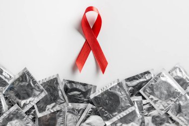 top view of aids awareness red ribbon and silver condoms on white background, medical concept clipart