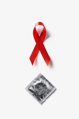 Beyaz arka plan üzerinde AIDS bilinçlendirme kırmızı şerit ve gümüş prezervatif üstten görünüm