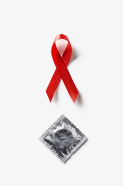 top view of aids awareness red ribbon and silver condom on white background clipart