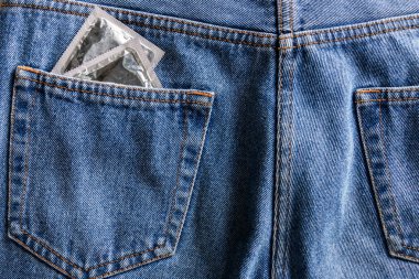 pair of silver condoms in pocket of blue jeans clipart