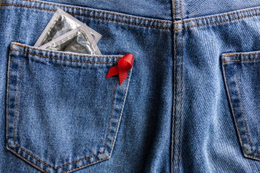 mavi jeans cebinde AIDS bilinçlendirme kırmızı şerit ve gümüş prezervatif