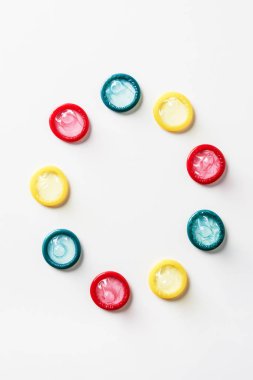 top view of multicolored condoms on white background clipart