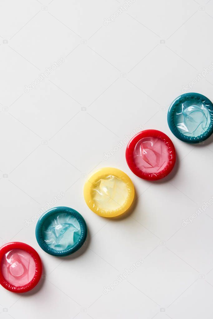 top view of multicolored condoms on white background