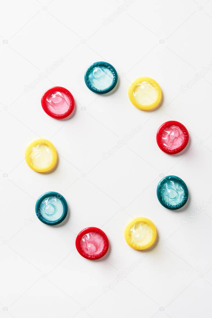 top view of multicolored condoms on white background