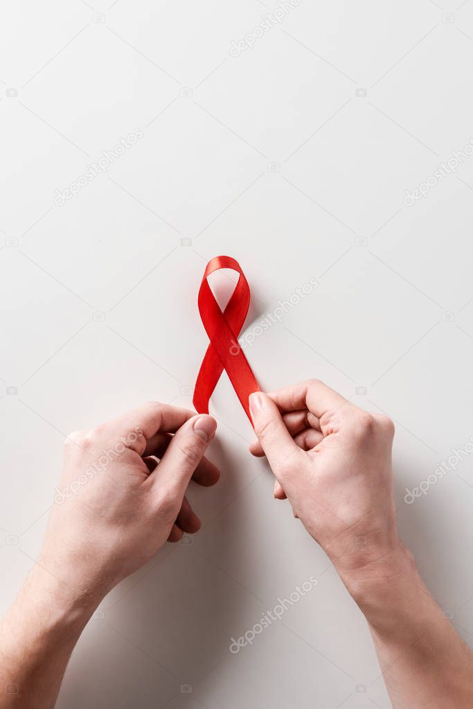 male hands holding aids awareness red ribbon on white background