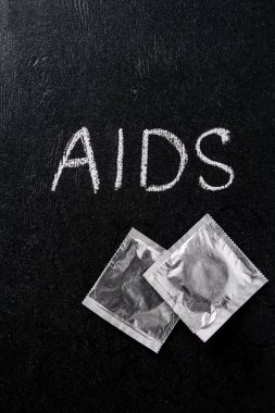 siyah arka plan üzerinde AIDS işareti ve gümüş prezervatif üstten görünüm
