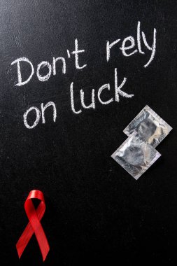siyah arka plan üzerinde AIDS bilinçlendirme kırmızı şerit ve gümüş prezervatif üstten görünüm