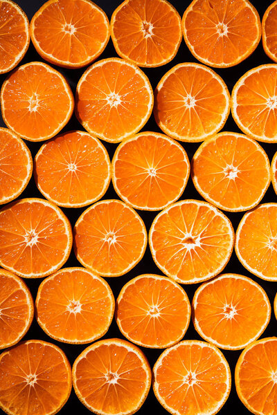 full frame of arranged cut tangerines halves on black background