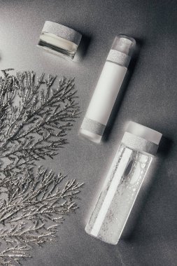düz lay losyon, micellar su ile krem kapsayıcı bir şekilde dekore edilmiş köknar ağacı yakınındaki gümüş şubeleri 