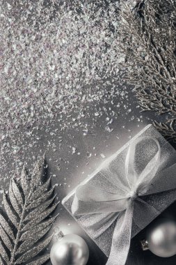 Gümüş üzerinde hediye kutusu, Noel topları ve dekore edilmiş dalları üstten görünüm 