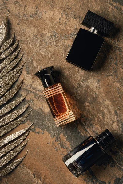 Vista Superior Perfumes Engarrafados Folhas Douradas Decorativas Superfície Intemperismo Marrom — Fotografia de Stock