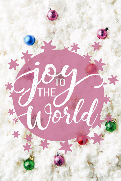 Верхний вид красочных рождественских игрушек на фоне белой ваты с вдохновением "радость миру"
