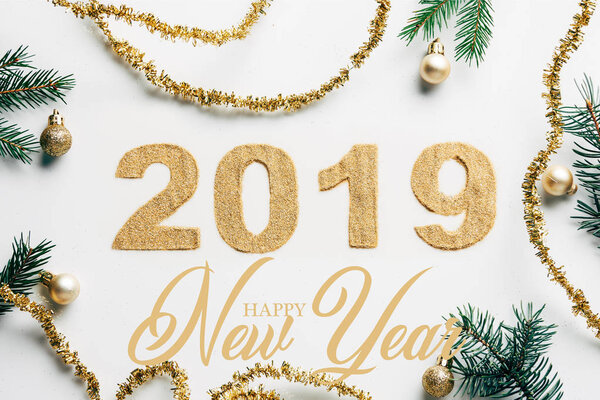 верхний вид знак 2019 года, сосновые ветви, золотые гирлянды и рождественские шары на белом фоне с надписью "С Новым годом"
