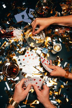 Sigara ve altın konfeti tarafından örtülü masasında poker oynamaya erkek kısmi görünümü