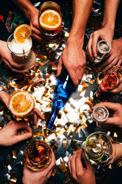 arkadaşlar spin oynamak çeşitli alkollü kokteyller ile kısmi görünümünü şişeyi masada tarafından altın konfeti kaplı. 