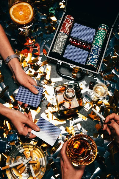 部分观点的妇女玩扑克在桌子上与威士忌 酒精鸡尾酒和香烟和金色的五彩纸屑 — 图库照片