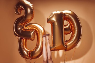 2019 numaraları bej, yeni yıl kavramı üzerinde partide Balonlar altında yatan kadının resim kırpılmış