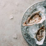 Top view of oysters with ice on metal tray on grey tabletop