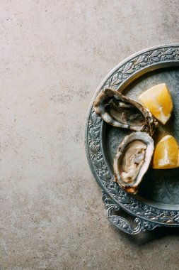 gri masa üzerinde metal tepsi üzerinde istiridye ve limon parçaları üstten görünüm