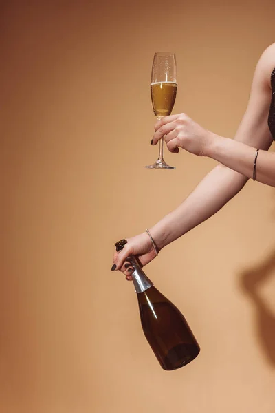 裁剪的妇女举行玻璃和香槟酒瓶在米色的党的形象 — 图库照片