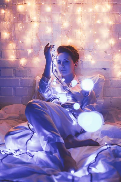 Beautiful Woman Pajamas Festive Lights Sitting Bed Home — Stock Photo, Image