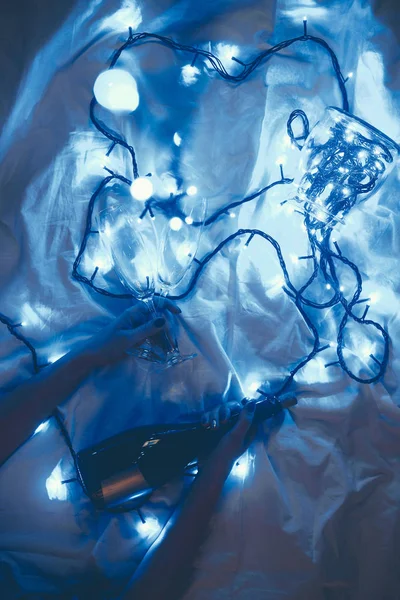 Обрізаний Знімок Жінки Пляшкою Шампанського Окулярами Ліжку Святковим Синім Світлом — Безкоштовне стокове фото