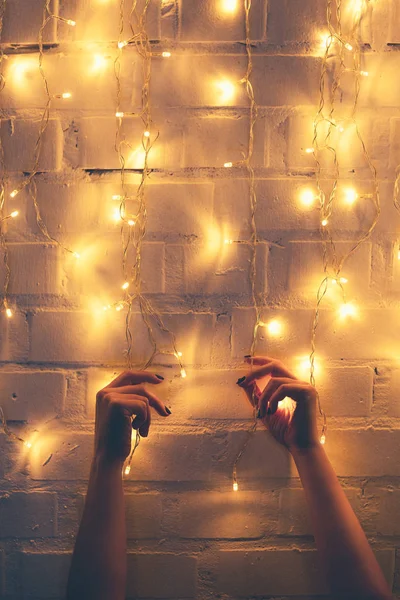 Teilansicht Einer Frau Mit Weihnachtsbeleuchtung Mit Backsteinmauer Hintergrund — Stockfoto