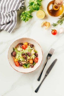 şişe ile beyaz kase yağ, kiraz domates, limon ve biberiye masada salataya 