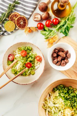 salata yağ, kiraz domates, limon ve biberiye yüzeyi şişe üstten görünüm üzerinde beyaz kase 