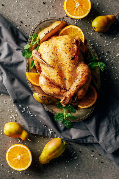 fried chicken with oranges, pears and greenery on tray 