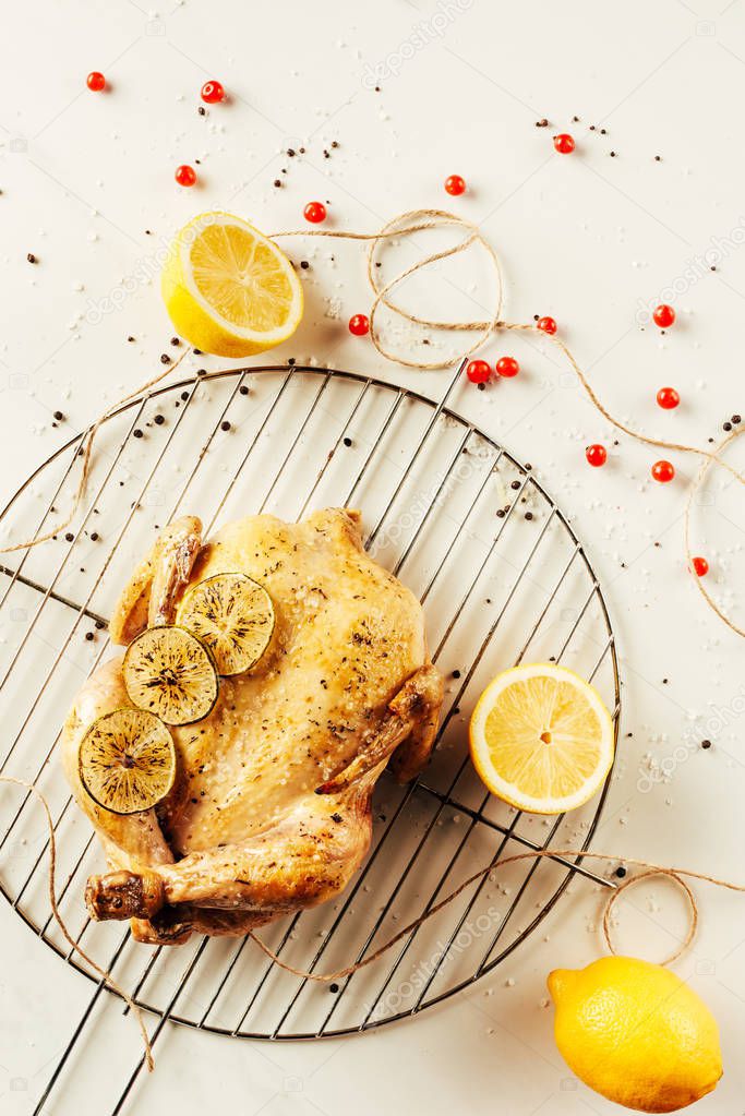 top view of fried chicken and lemons on metal grille with berries and string