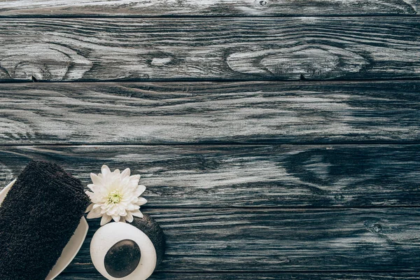 Вид сверху на спа и массажные принадлежности с полотенцем, галькой и цветком хризантемы на деревянном фоне — стоковое фото