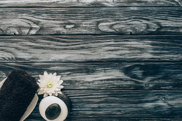 Top view of arranged spa and massage accessories with towel, pebbles and chrysanthemum flower on wooden background — Stock Photo