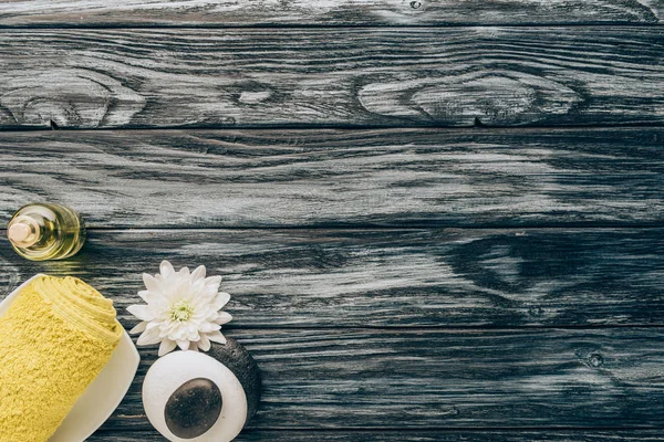 Draufsicht auf arrangierte Wellness- und Massageaccessoires mit Handtuch, Kieselsteinen und ätherischem Öl auf Holzgrund — Stockfoto