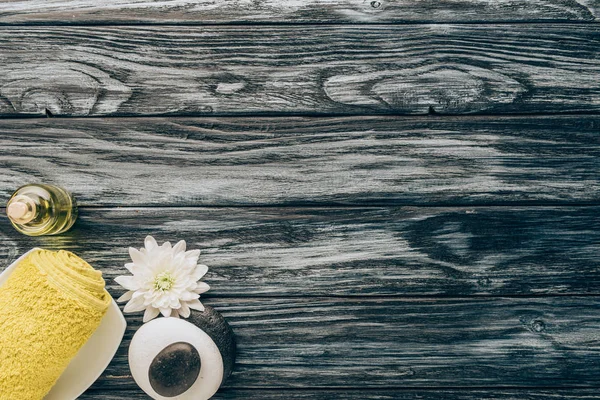 Top view of arranged spa and massage accessories with towel, pebbles and essential oil on wooden background — Stock Photo