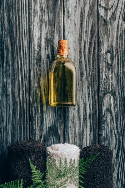 Top view of arranged essential oil, towels and fern plant for spa and massage on wooden tabletop — Stock Photo