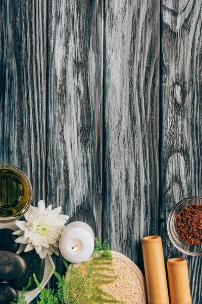 Vista superior de guijarros arreglados, aceite, sal y palos de bambú para spa y masaje sobre fondo de madera - foto de stock