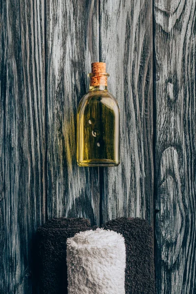 Top view of arranged essential oil and towels for spa and massage on wooden background — Stock Photo