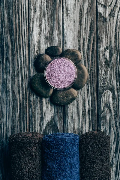 Flat lay with spa and massage treatment arrangement with salt, towels and pebbles on wooden tabletop — Stock Photo