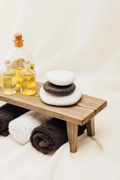 Close up view of arrangement of spa treatment accessories with towels, oil and pebbles on white background — Stock Photo