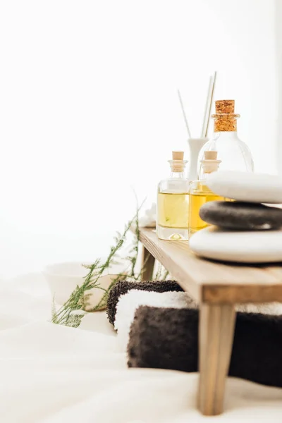 Vista ravvicinata della disposizione degli accessori per il trattamento termale con pianta di felce, asciugamani, olio e sale su sfondo bianco — Foto stock
