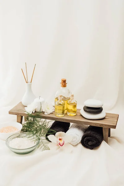 Vue rapprochée de l'arrangement des accessoires de traitement spa avec fleur d'orchidée, serviettes, huile et sel sur fond blanc — Photo de stock