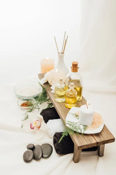 Close up view of arrangement of spa treatment accessories with towels, oil and salt on white background — Stock Photo
