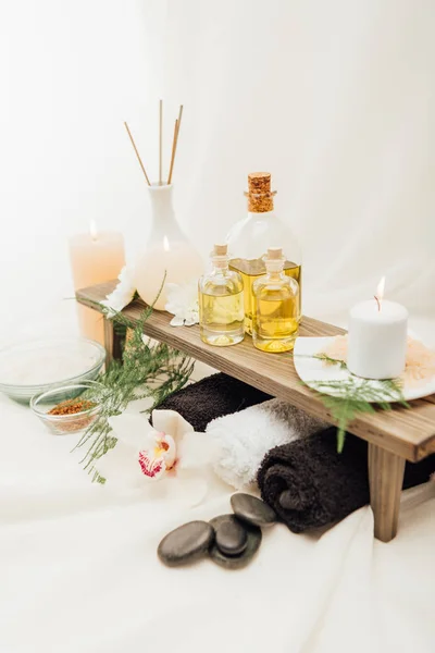 Vista de cerca de la disposición de los accesorios de tratamiento de spa con aceite esencial, sal y vela sobre fondo blanco - foto de stock