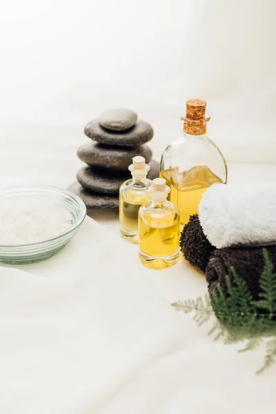 Close up view of arrangement of spa treatment accessories with essential oil, pebbles and salt on white background — Stock Photo
