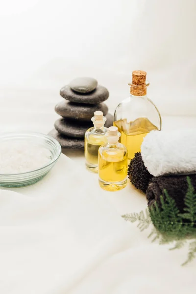 Vista de cerca de la disposición de los accesorios de tratamiento de spa con aceite esencial, guijarros y sal sobre fondo blanco - foto de stock